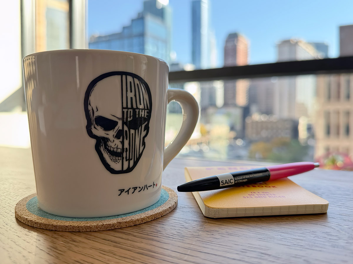A coffee mug, notebook, and pen on a café table